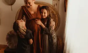 Laura, the Swedish family, väntar sitt tredje barn. Barnen kramar mammans mage med kärlek.