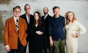 Michael Storåkers med kollegor, en grupp på sex personer, poserar framför en ljus vägg.