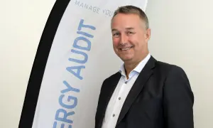 Thomas Ekman ler glatt framför en banderoll med texten "ENERGY AUDIT".