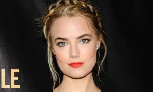 Rebecca Rittenhouse med flätat hår och rött läppstift, blickar mot kameran.