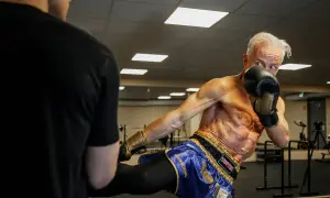 Ola Ahlvarsson, en äldre man med imponerande fysik, utför en spark under kickboxningsträning.