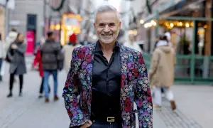 Panos Papadopoulos, en man med grått hår och skägg, ler i en färgglad kavaj med dödskallemönster.