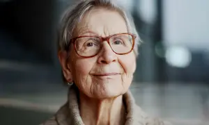Kerstin Brunnberg, en äldre kvinna med glasögon och grått hår, ler mjukt.