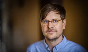 Sune Kempe, en man med glasögon och blå skjorta, tittar in i kameran.