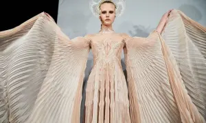 En modell bär en skapelse av Iris van Herpen med böljande, veckade ärmar och en utsmyckad överdel.