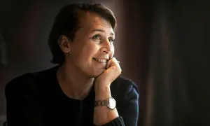 Hanna Widell ler och vilar hakan i handen, klädd i en mörk tröja med en klocka på handleden.