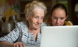 En äldre kvinna och en ung flicka tittar på en laptop. De lär sig om nya medier, en kontrast till traditionella medier.