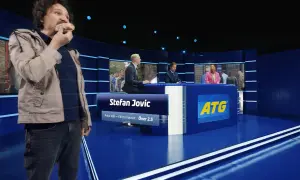 Man äter korv i en studio med ATG-reklam.