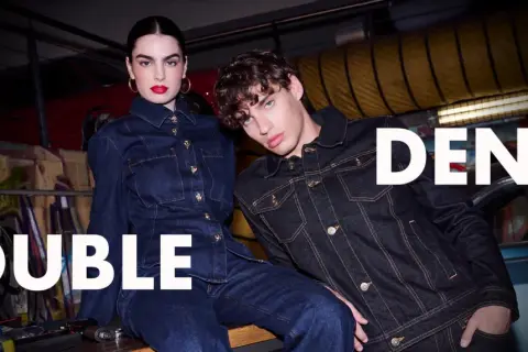 Två modeller i mörka denimkläder, en kvinna och en man, visar upp den senaste denim on denim-trenden.