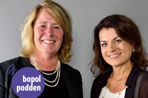 Två leende kvinnor, en med pärlhalsband, den andra med guldsmycken. Johanna Frelin är en av dem.