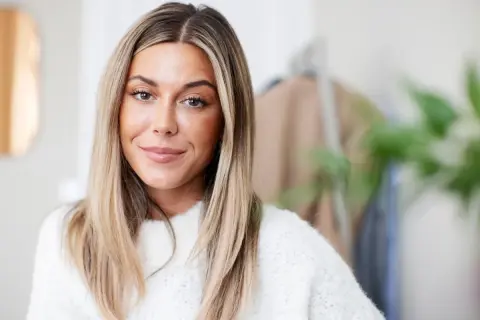 En kvinna med blont hår och en vit tröja, kanske en av Sveriges rikaste influencers.
