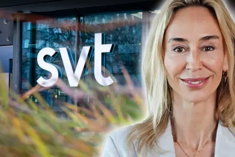 En kvinna med blont hår ler mot kameran framför SVT-loggan. Hon är en av SVT:s kvinnliga programledare.