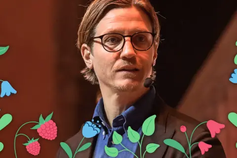 Alexander Lydecker med glasögon och blå skjorta, omgiven av blommor och hallon.