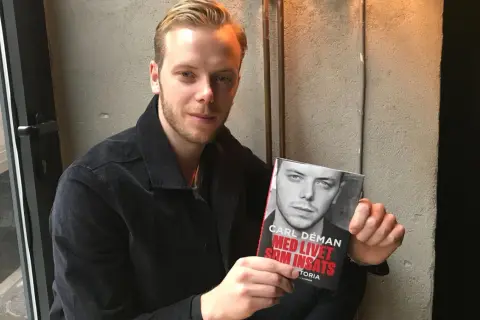 Carl Déman håller upp sin bok "Med livet som insats".