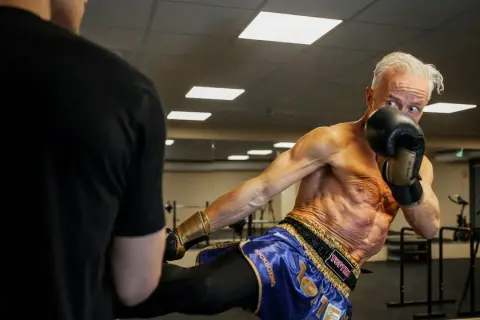 Ola Ahlvarsson, en äldre man med imponerande fysik, utför en spark under kickboxningsträning.