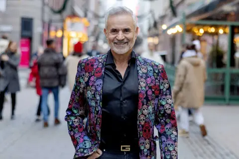 Panos Papadopoulos, en man med grått hår och skägg, ler i en färgglad kavaj med dödskallemönster.