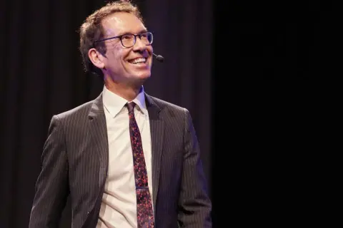 Byron Sharp ler glatt på scenen, klädd i kostym och slips, redo att dela med sig av sina insikter.