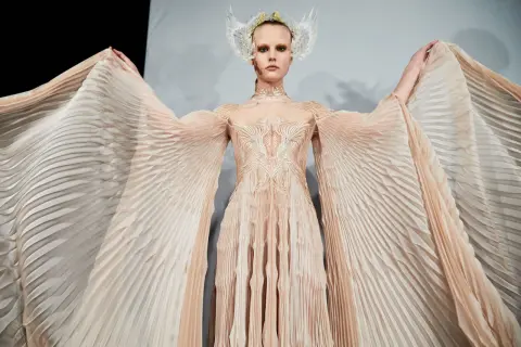 En modell bär en skapelse av Iris van Herpen med böljande, veckade ärmar och en utsmyckad överdel.