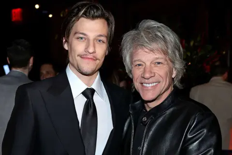 Jesse Bongiovi och Jon Bon Jovi ler mot kameran. Jesse bär en svart kostym och Jon en svart läderjacka.