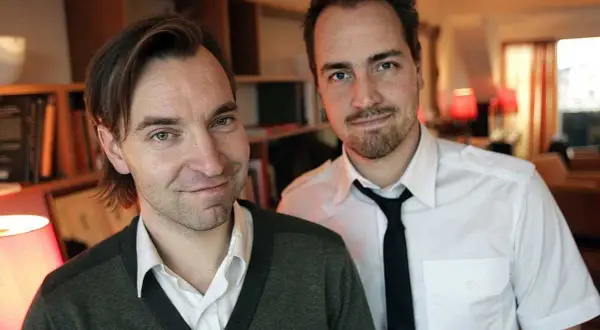 Två män, varav en är Måns Mårlind, poserar framför bokhyllor.