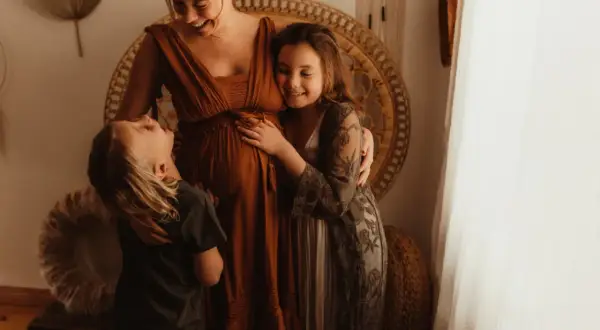 Laura, the Swedish family, väntar sitt tredje barn. Barnen kramar mammans mage med kärlek.