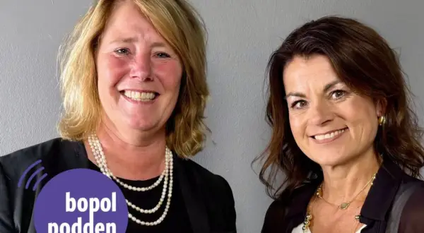 Två leende kvinnor, en med pärlhalsband, den andra med guldsmycken. Johanna Frelin är en av dem.