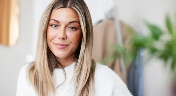 En kvinna med blont hår och en vit tröja, kanske en av Sveriges rikaste influencers.