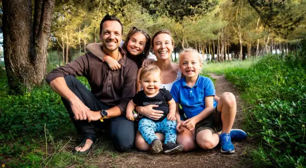 En glad axel swedish family med tre barn i en skog.