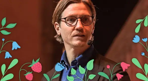 Alexander Lydecker med glasögon och blå skjorta, omgiven av blommor och hallon.