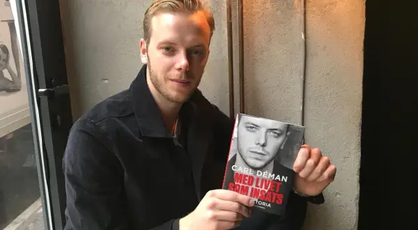 Carl Déman håller upp sin bok "Med livet som insats".