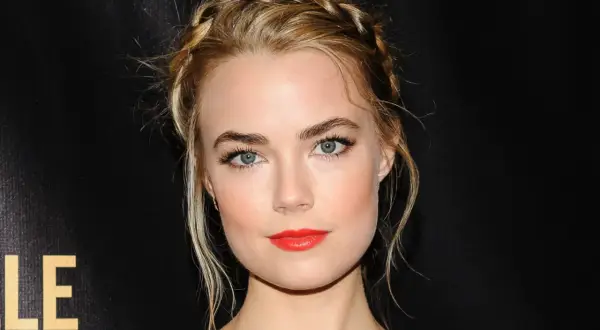 Rebecca Rittenhouse med flätat hår och rött läppstift, blickar mot kameran.