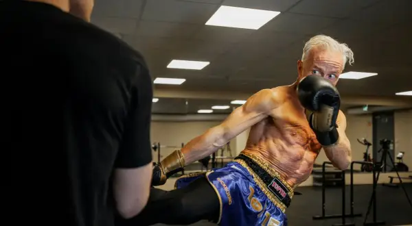 Ola Ahlvarsson, en äldre man med imponerande fysik, utför en spark under kickboxningsträning.