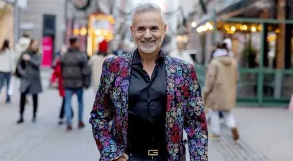 Panos Papadopoulos, en man med grått hår och skägg, ler i en färgglad kavaj med dödskallemönster.