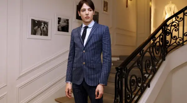 Harry Brant står på en trappa i en randig kostym.