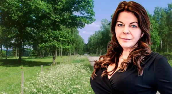 Jennifer Wegerup i en vacker sommarmiljö med en väg kantad av träd och blommor.