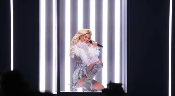 Veronica Silvstedt sjunger på scenen i en glittrig outfit, omgiven av starka ljus.
