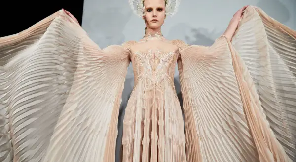 En modell bär en skapelse av Iris van Herpen med böljande, veckade ärmar och en utsmyckad överdel.