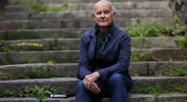 Johan af Donner sitter på en trappa utomhus, klädd i en mörkblå jacka och jeans. En anteckningsbok ligger bredvid honom.