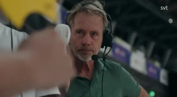 En svt sport medarbetare med headset och mikrofon, redo att rapportera från en sportarena.