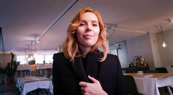 Karin Winther ler mot kameran i en restaurang.