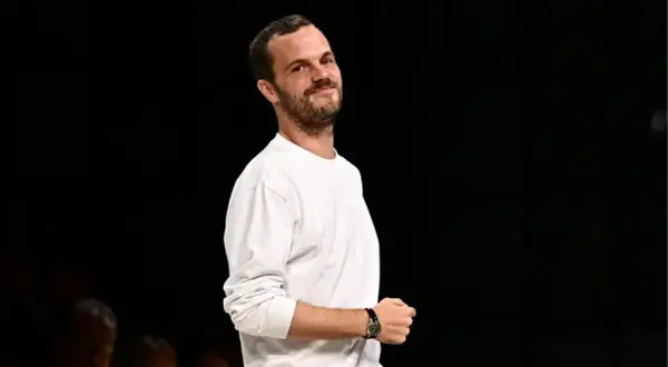 Matthieu Blazy, klädd i en vit långärmad tröja, ler mot kameran.