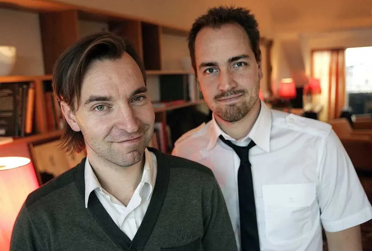 Två män, varav en är Måns Mårlind, poserar framför bokhyllor.