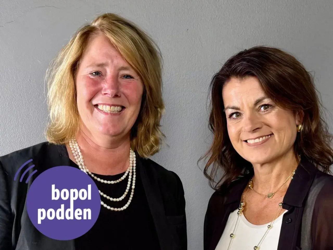 Två leende kvinnor, en med pärlhalsband, den andra med guldsmycken. Johanna Frelin är en av dem.