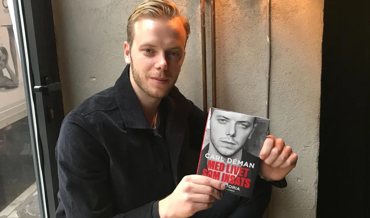 Carl Déman håller upp sin bok "Med livet som insats".