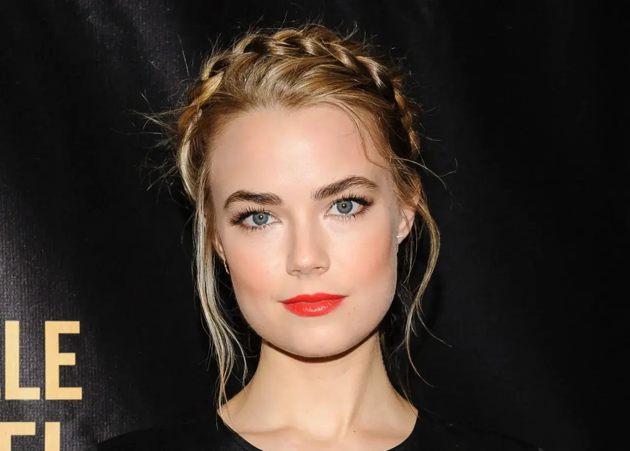 Rebecca Rittenhouse med flätat hår och rött läppstift, blickar mot kameran.