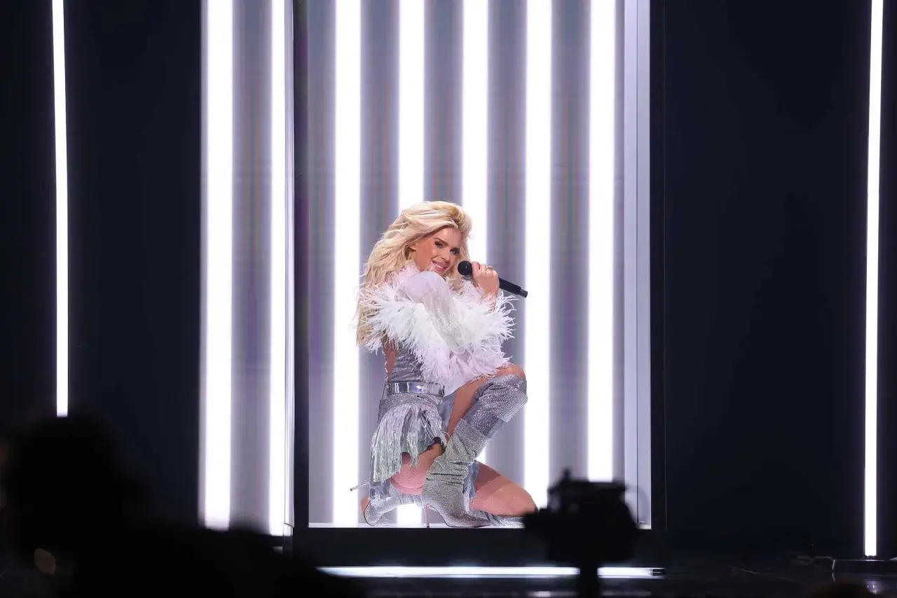 Veronica Silvstedt sjunger på scenen i en glittrig outfit, omgiven av starka ljus.