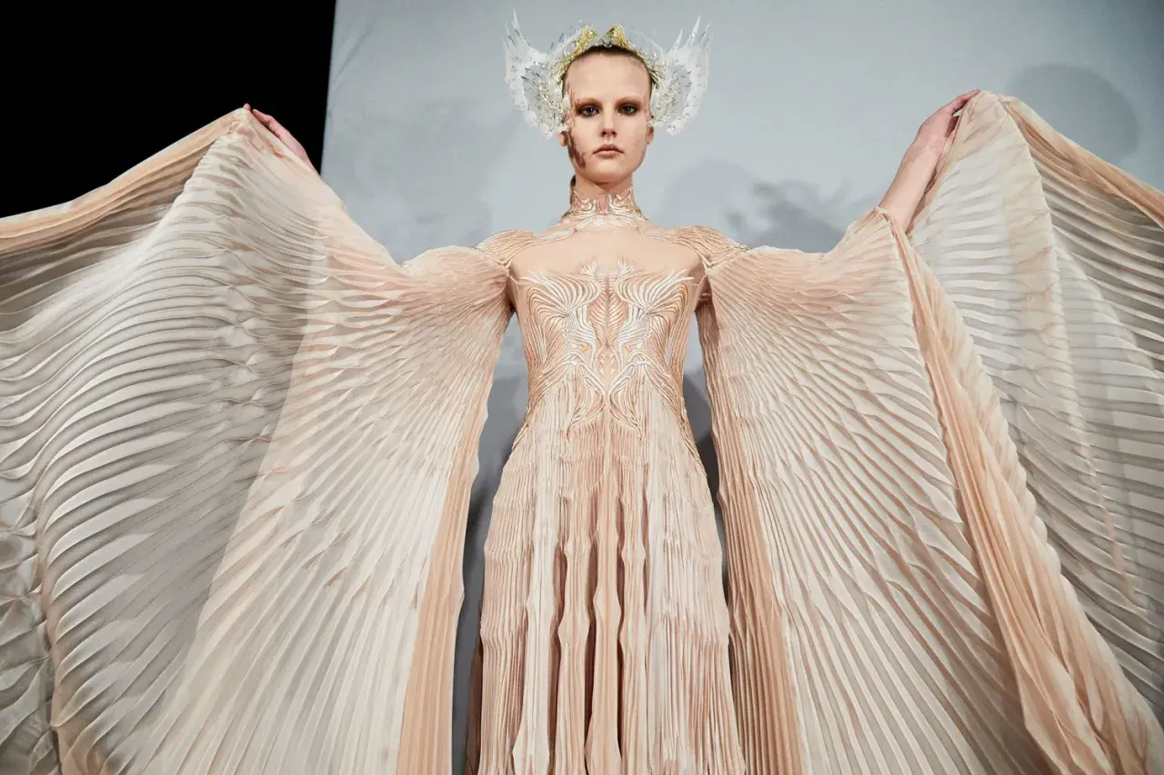 En modell bär en skapelse av Iris van Herpen med böljande, veckade ärmar och en utsmyckad överdel.