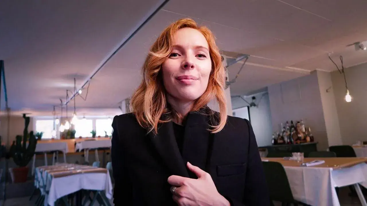 Karin Winther ler mot kameran i en restaurang.
