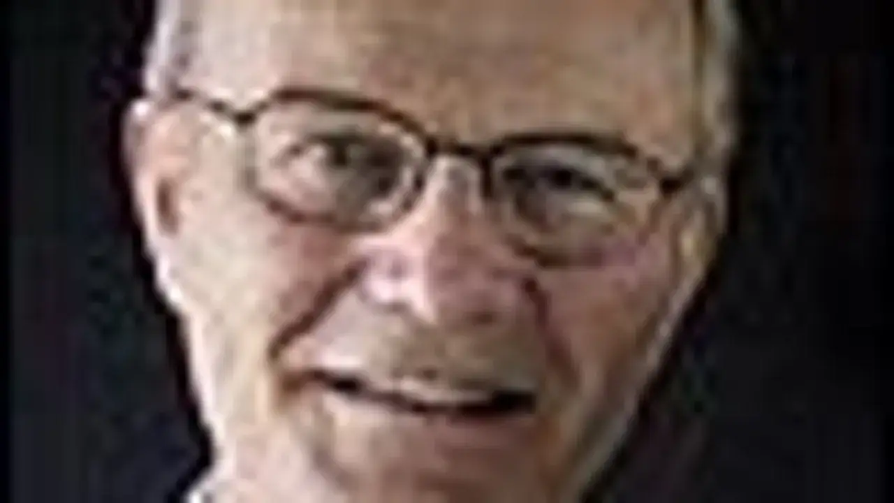 Närbild på Olle Stenholm med glasögon, mörkt hår och en vänlig blick.