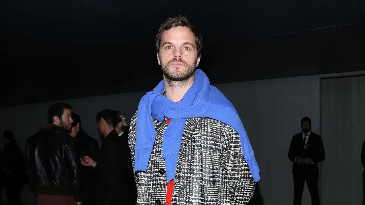 Matthieu Blazy, kl&auml;dd i en rutig jacka och bl&aring; tr&ouml;ja, blickar mot kameran.